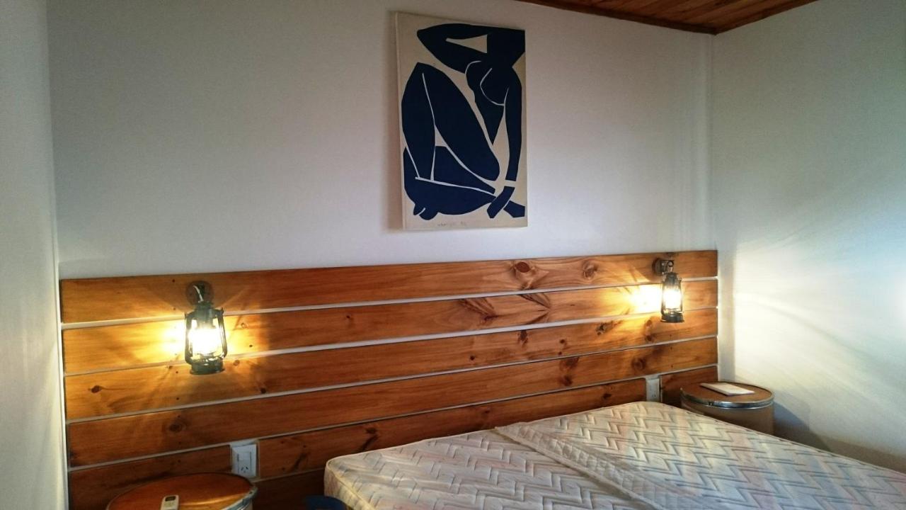 Dormitorio de cabaña con cabecera de madera, luces cálidas y decoración moderna